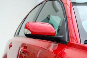 Profile of red luxury sports sedan. Focus on side mirror.